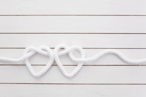 Hartvormige knoop op witte houten achtergrond — Stockfoto