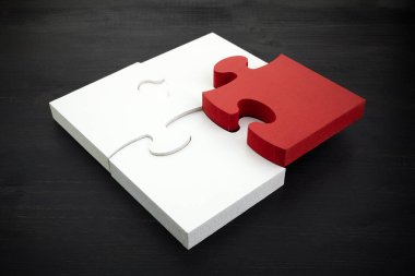 Üç onnected yapboz parçaları ve koyu ahşap arka plan üzerinde bir kırmızı. Ekip çalışmasında doğru çözümleri bulmak.