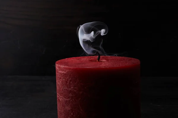 Red extinguished candle with smoke trailing off the wick on black background — Stock Photo, Image