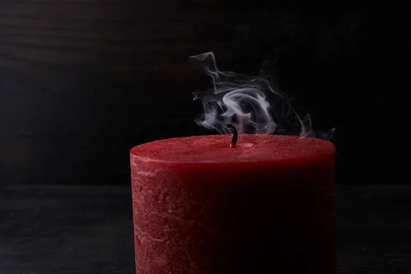 Red extinguished candle with smoke trailing off the wick on black background — Stock Photo, Image