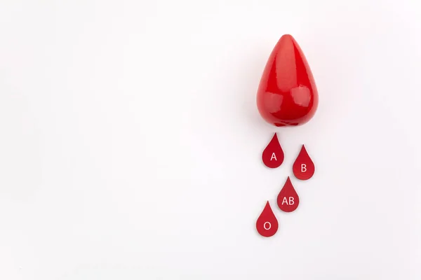 Blod droppar med olika blod typer på vit bakgrund med kopierings utrymme — Stockfoto