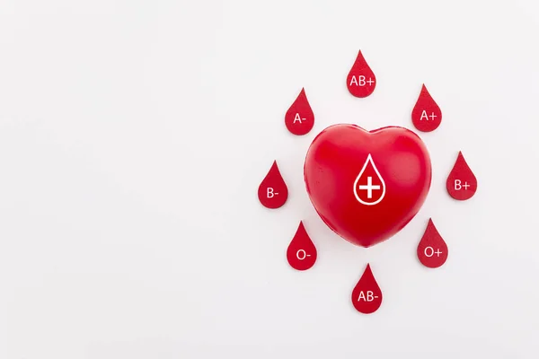 Hjärta och blod droppar med olika blod typer på vit bakgrund. Uppifrån och — Stockfoto