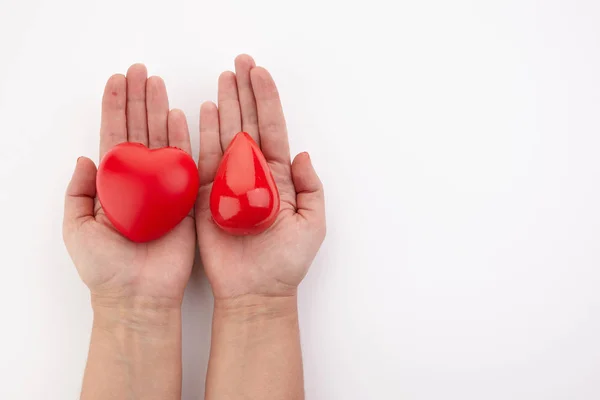 Två händer som håller rött blod droppe och hjärta på vit bakgrund. Ge blod. Donation begrepp. — Stockfoto