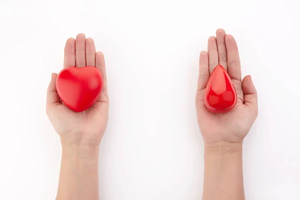 Due mani che tengono la goccia di sangue rosso e il cuore su sfondo bianco. Dare sangue. Concetto di donazione . — Foto Stock