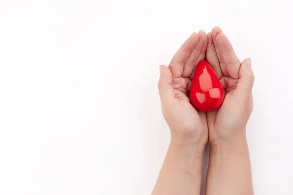 Twee handen vasthouden rode bloed drop op witte achtergrond. Geef bloed. Donatie concept. — Stockfoto