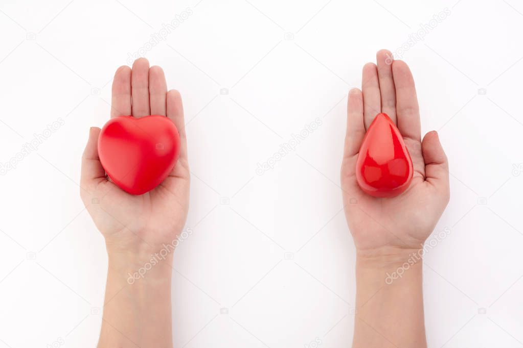 Two hands holding red blood drop and heart on white background. Give blood. Donation concept.