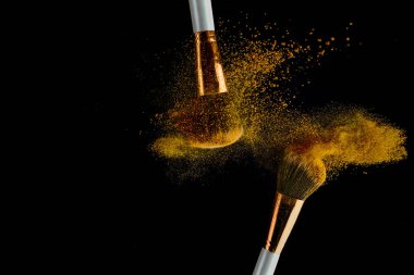 Siyah arka plan üzerinde yayılan altın tozu ile Kozmetik fırça