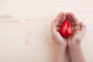 Beyaz arka planda kırmızı kan damlası tutan iki el. Kan verin. Bağış kavramı.