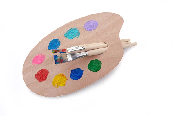 Tavolozza di legno con colori e pennelli isolati su sfondo bianco — Foto Stock