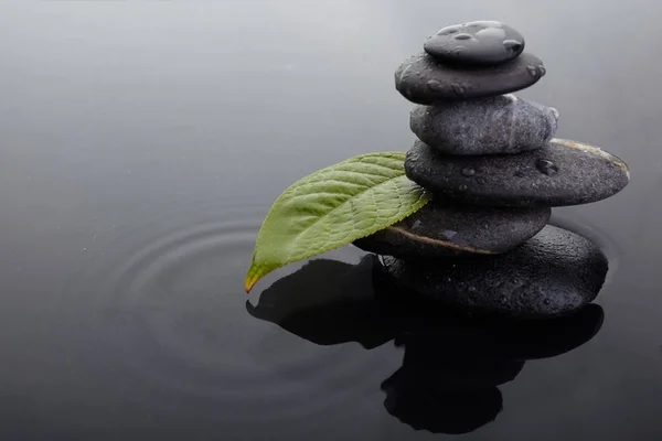 Pietre zen in pila equilibrata e foglia verde con gocce d'acqua in acqua — Foto Stock