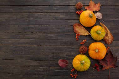 Ahşap arka planda balkabakları ve düşmüş yapraklar. Cadılar Bayramı, Şükran Günü veya mevsimsel geçmiş