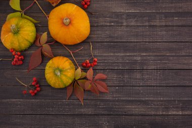 Ahşap arka planda balkabakları ve düşmüş yapraklar. Cadılar Bayramı, Şükran Günü veya mevsimsel geçmiş