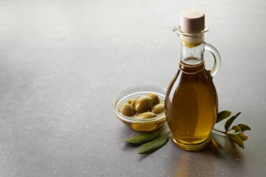 Gri arka planda zeytin yağı ve zeytin dalı