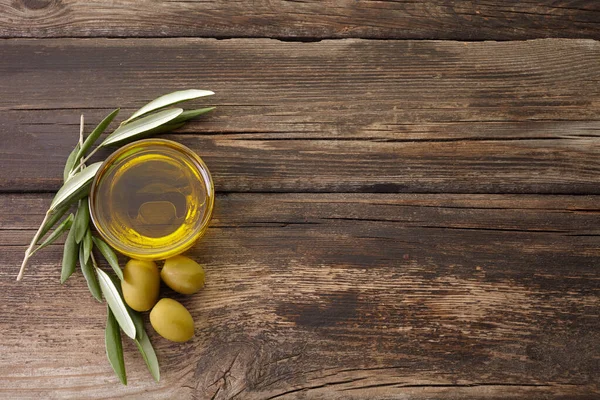 Azeite e ramo de oliveira retroiluminado no fundo de madeira velho — Fotografia de Stock