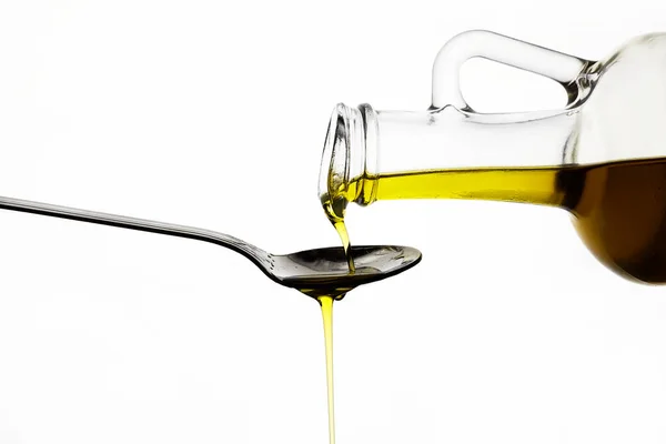 Versando olio d'oliva da bottiglia di vetro su fondo bianco — Foto Stock