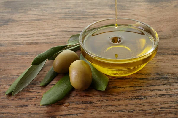 Оливковое масло и оливковая ветвь подсветки на старом деревянном фоне — стоковое фото