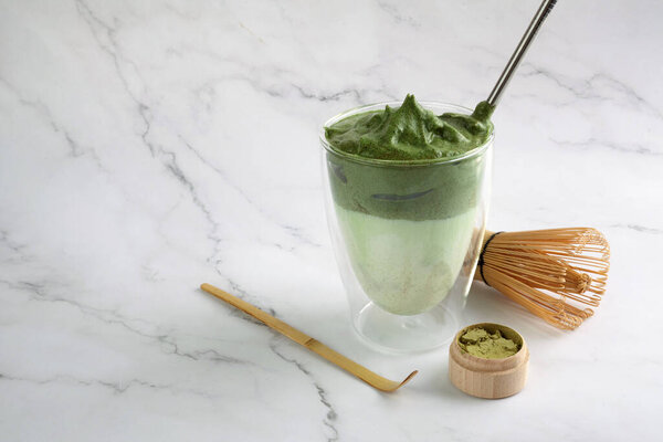 Green matcha dalgona. Trendy hipster drink on marble background.