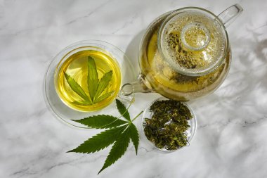 Kenevir bitki çayı. Hafif arka planda kenevir yapraklı sıcak içecek.