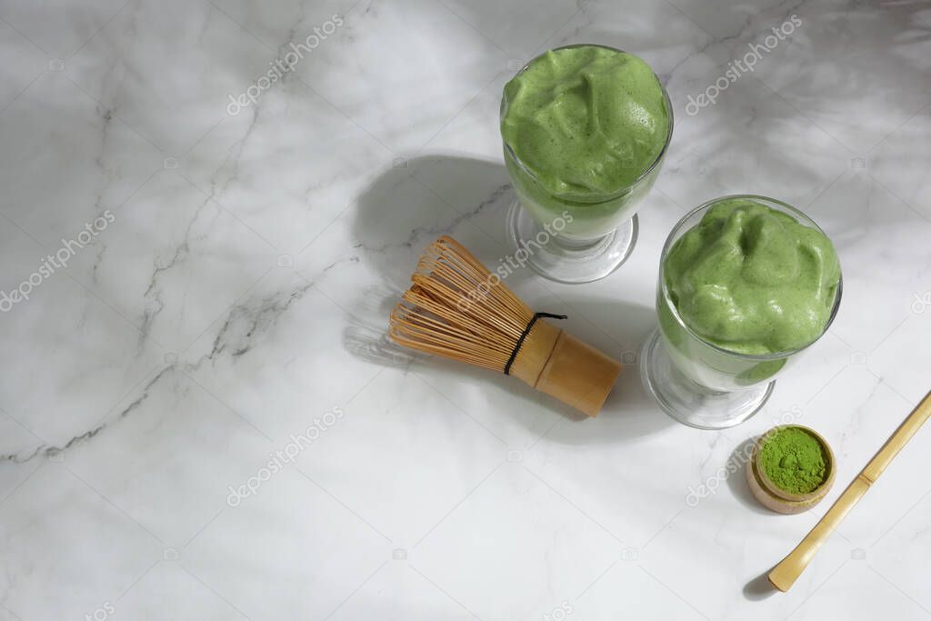 Green matcha dalgona. Trendy hipster drink on marble background.