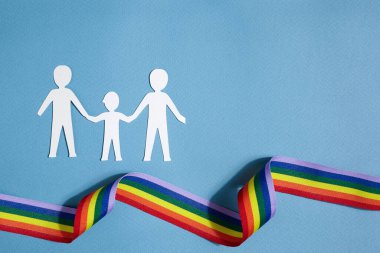Homoseksüel aile. Farklı bir aile. Kağıt yağmur kurdelesiyle aile simgesini kesti