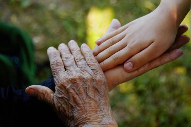 Yaşlı kadınlar ve genç çocuk el ele tutuşuyor. Aile sevgisi kavramı.