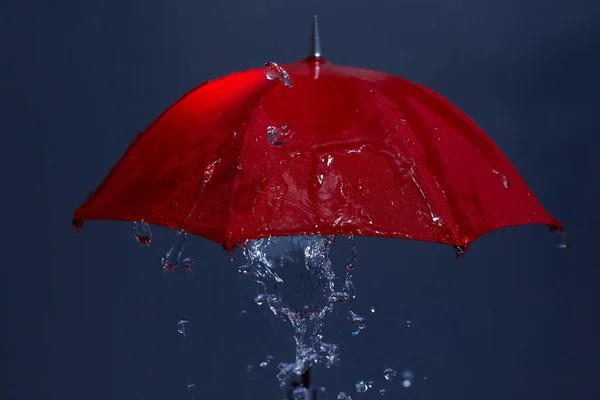 Gotas de lluvia cayendo del paraguas rojo. Concepto de mal tiempo. — Foto de Stock