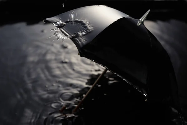 Des gouttes de pluie tombent du parapluie noir. Concept de mauvais temps. — Photo