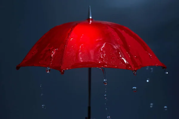 Regentropfen fallen vom roten Regenschirm. Schlechtwetterkonzept. — Stockfoto