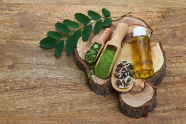 Ahşap bir yüzeyde doğal moringa ürünleri, yapraklar, toz, tohumlar ve petrol.