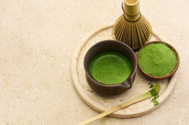 Taş zemin üzerinde kase, toz ve bambu çırpıcı ile kibrit çayının üst görüntüsü.