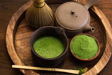 Bir kibrit çay tozu, bir çırpı ve bir çaydanlık ile ahşap tepside kırsal bir düzen..