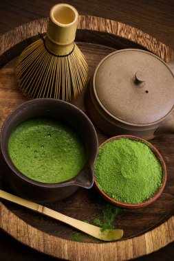 Canlı yeşil toz ve geleneksel aletlerle ahşap tepside kibrit çay setinin zarif bir gösterisi..