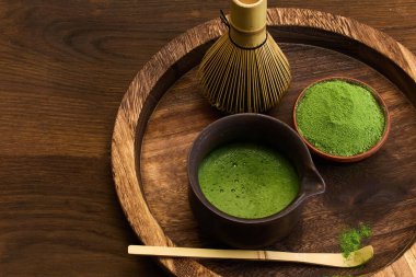 Tahta tepside bambu çırpıcı, kase ve yeşil çay tozu ile geleneksel bir kibrit çay seti..