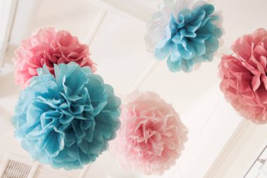 Çatı kirişlerinden sarkan pembe ve mavi peçeteli ponponlar, kutlamalar için mükemmel bir görüntü, bebek duşları vs.