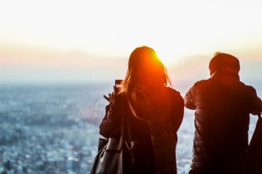 İnsanlar bir gözlem güvertesinde şehre bakıyorlar.