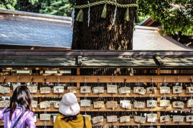 People standing in front of wooden Ema votive plaques at Meiji Jingu Shrine in Tokyo clipart