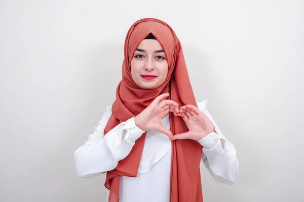 Genç hijab müslüman kadın parmaklarıyla bir kalp jesti yapıyor, Müslüman kız jest aşk kalp işareti