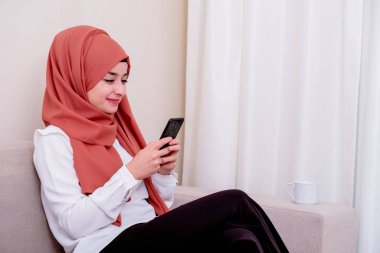 Müslüman bir kız akıllı telefonla mesaj yazıyor ya da sosyal medya kullanıyor ve mutlu.