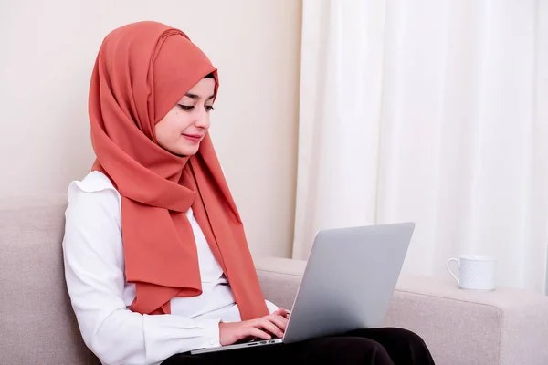 Muslim woman using computer and typing mail message