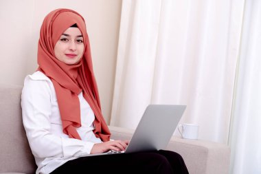 Müslüman kız dizüstü bilgisayar veya bilgisayar kullanmak, o kamera ve oturma ofis veya ev arıyorum