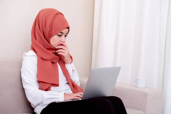 Muslim woman using computer for work and she thinking at home