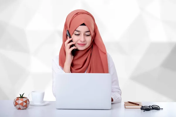 Muslim woman work with computer, hijab muslim girl at office and she is talking on mobile phone, support, contact or customer service concept photo