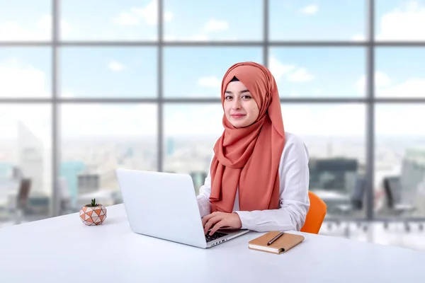 Hijab muslim woman work with computer, muslim girl sitting in office and look at the camera