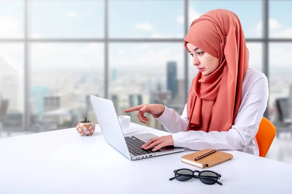 Muslim woman work with computer in office, hijab muslim girl pointing laptop screen