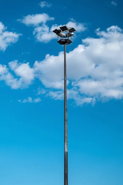 Street light pole, galvanized steel stadium or park lamp pole, electricity or steel industry photo, sky is blue and cloudy