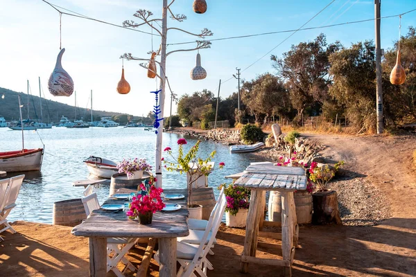 Bodrum, Gumusluk Town 'daki Ege balık lokantası masası. Restoran masaları ve sandalyeler denizde.