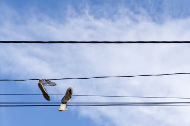 Kablolarda asılı bir çift spor ayakkabı Bulutlu mavi bir gökyüzüne