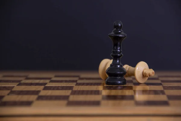 white piece of chess in the center surrounded by black pieces thrown