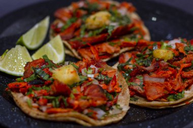 Domuz eti, ananas, kişniş ve soğan ile tacos siyah bir tabak ve siyah bir arka plan