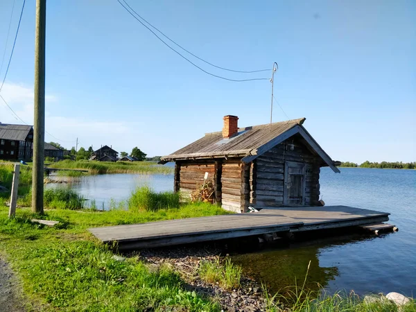 Wooden house by the lake in traditional russian village during summer.